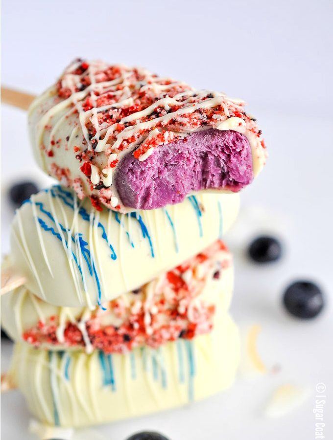 Blueberry Coconut Popsicles are a delightful blend of berries, coconut yogurt and milk dipped in decadent white chocolate and toasted coconut and freeze-dried berries.