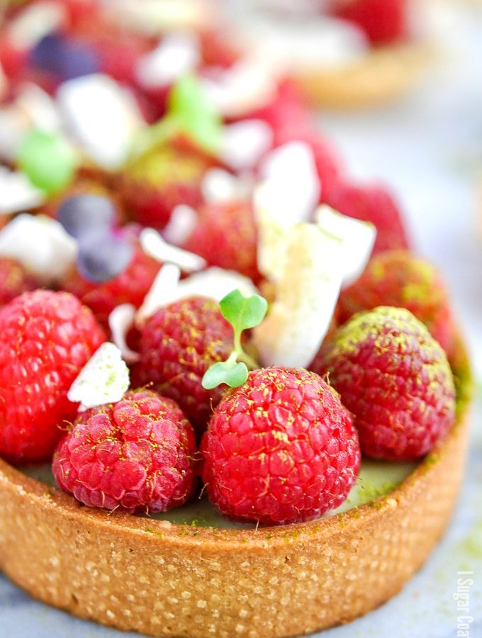 A delightful Coconut Matcha Ganache Tart with layers of silky green tea coconut ganache, raspberries and toasted coconut in a homemade sweet pastry.