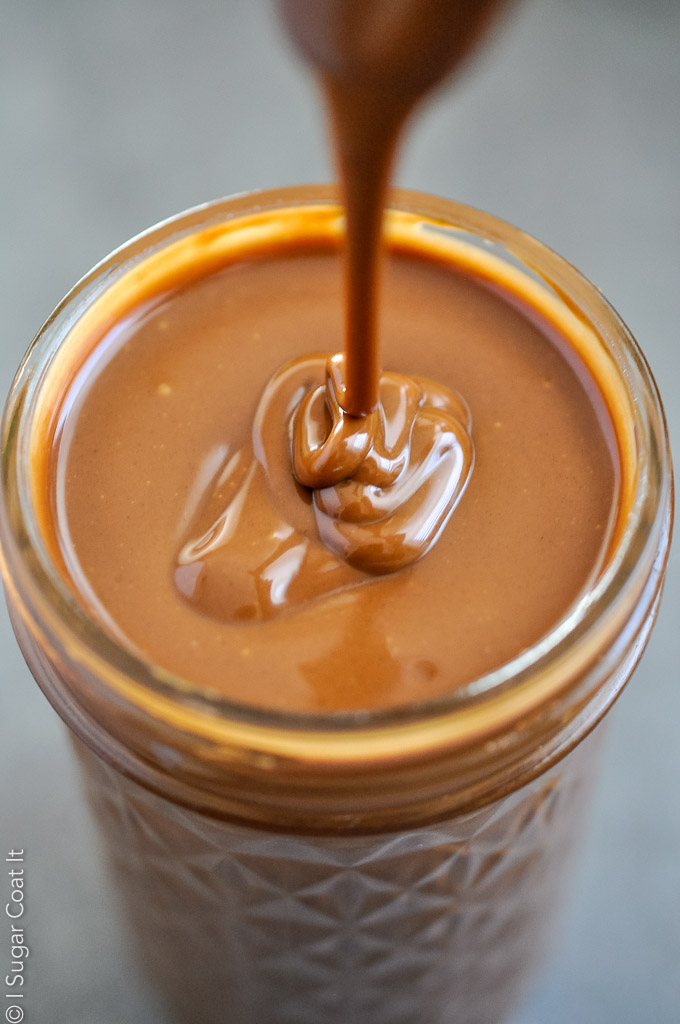 silky, dark hazelnut cacao nibs praline paste being poured into a jar | i sugar coat it